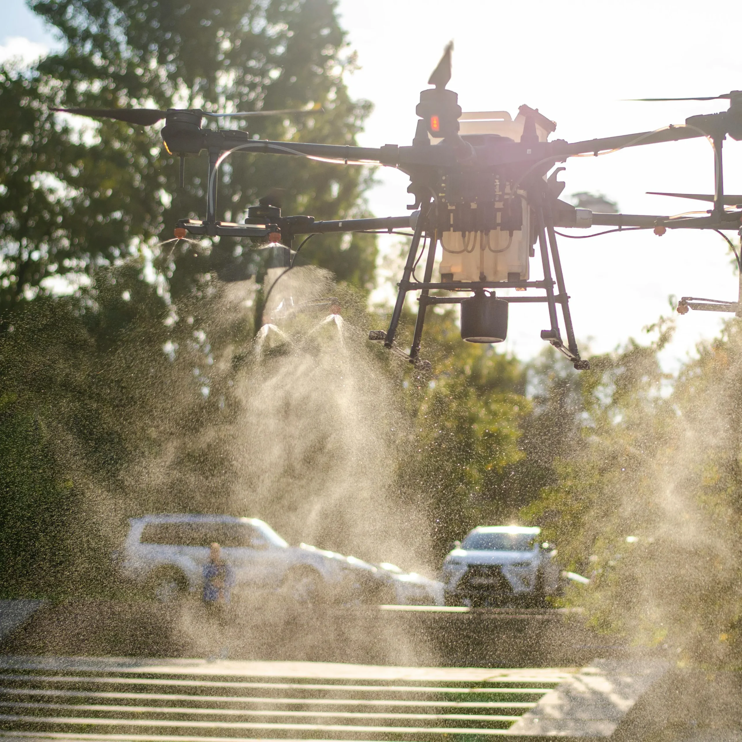 Agrarische drone sproeit vloeistof over een veld bij zonnig weer.