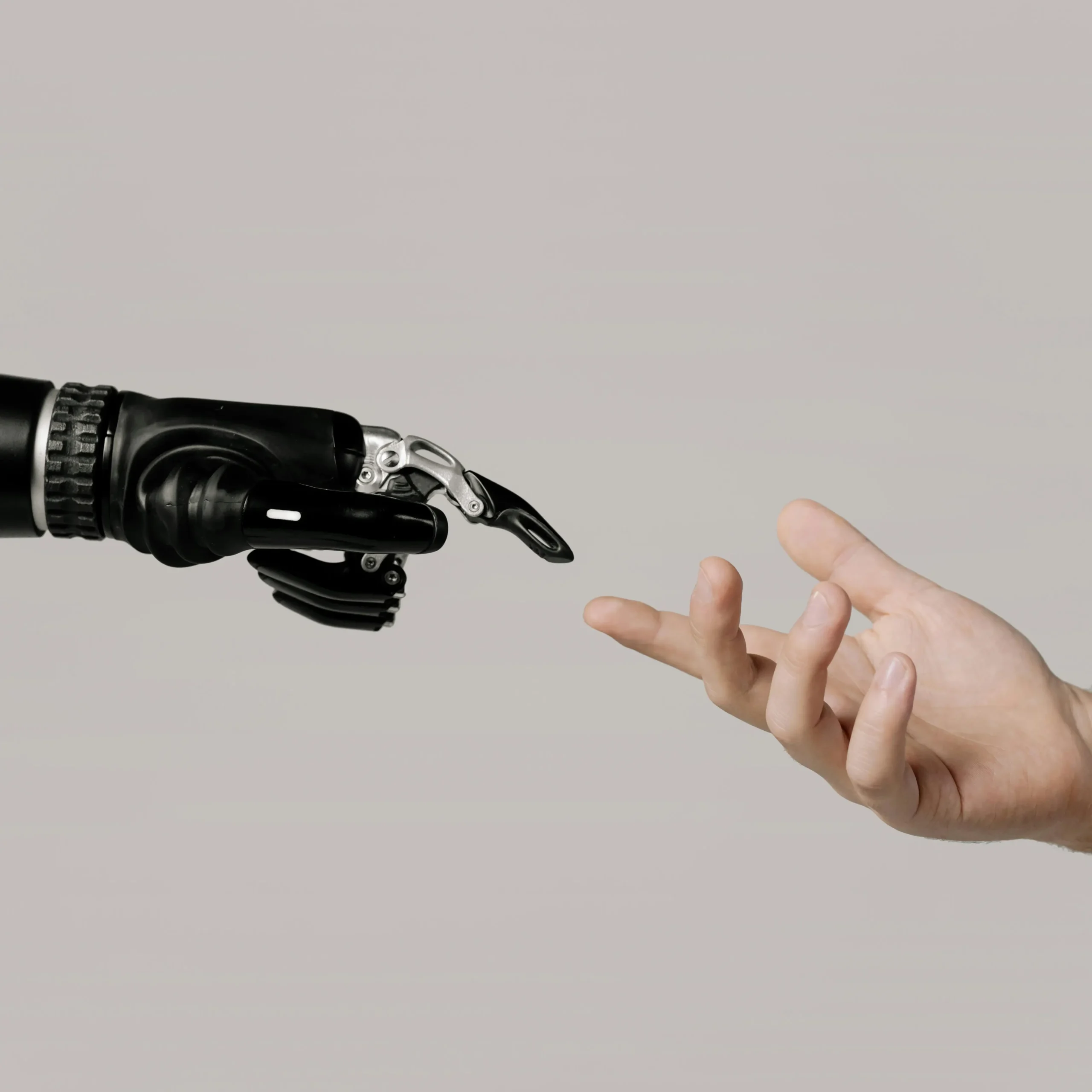 Robotische hand en menselijke hand reiken naar elkaar tegen een neutrale achtergrond.